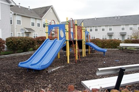 a playground with slides and benches in front of houses
