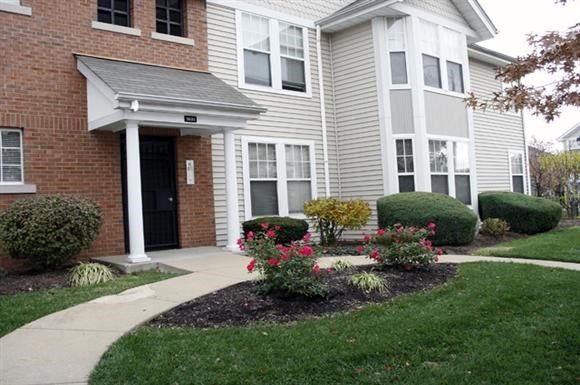 a house with a sidewalk and flowers in front of it