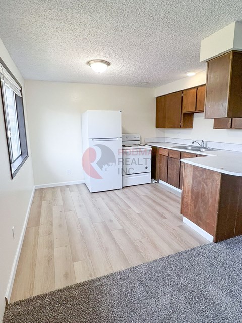 A kitchen with a white fridge and wooden cabinets.