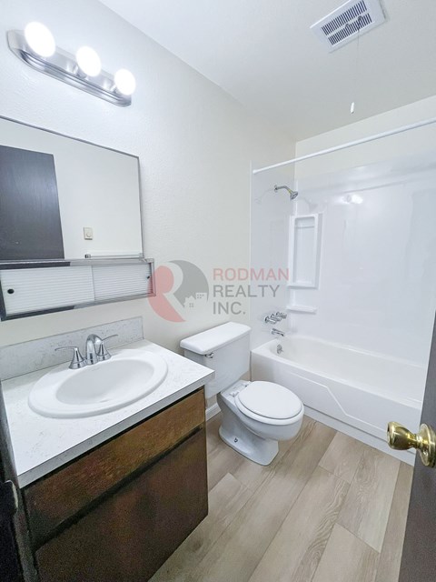 A bathroom with a toilet, sink, and mirror.