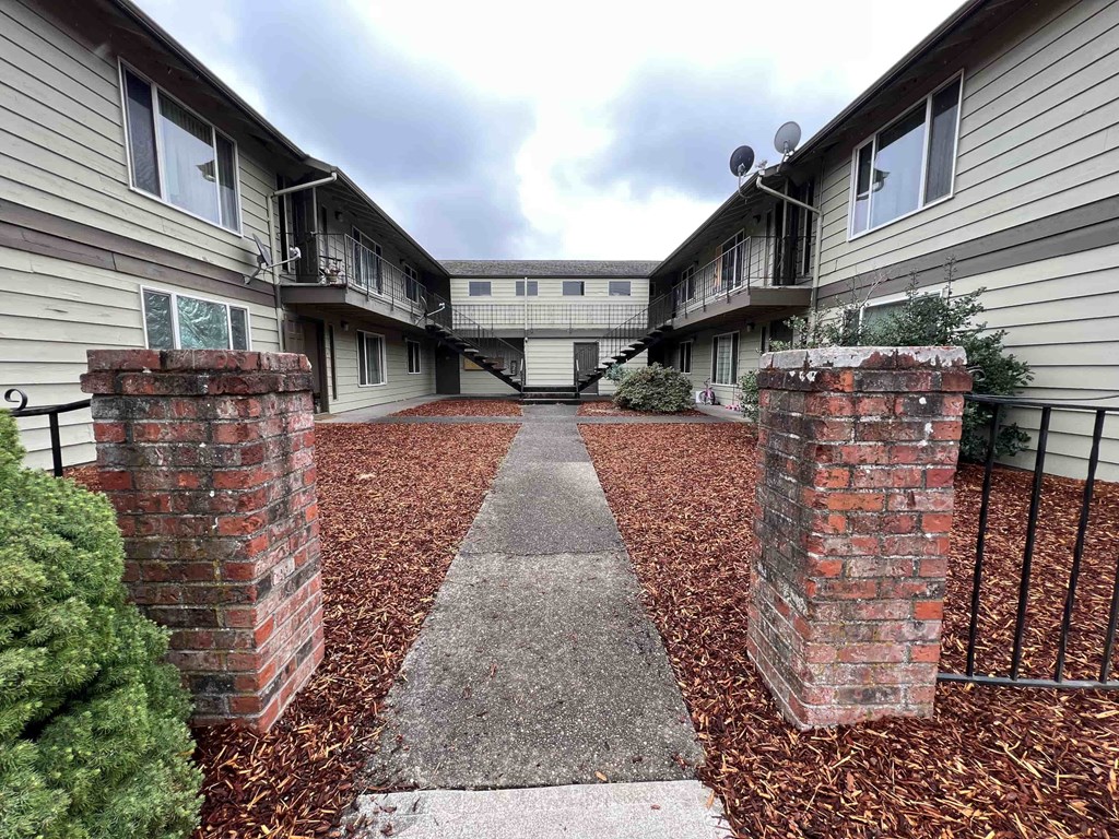 A courtyard with a brick pillar and a concrete path in the middle.