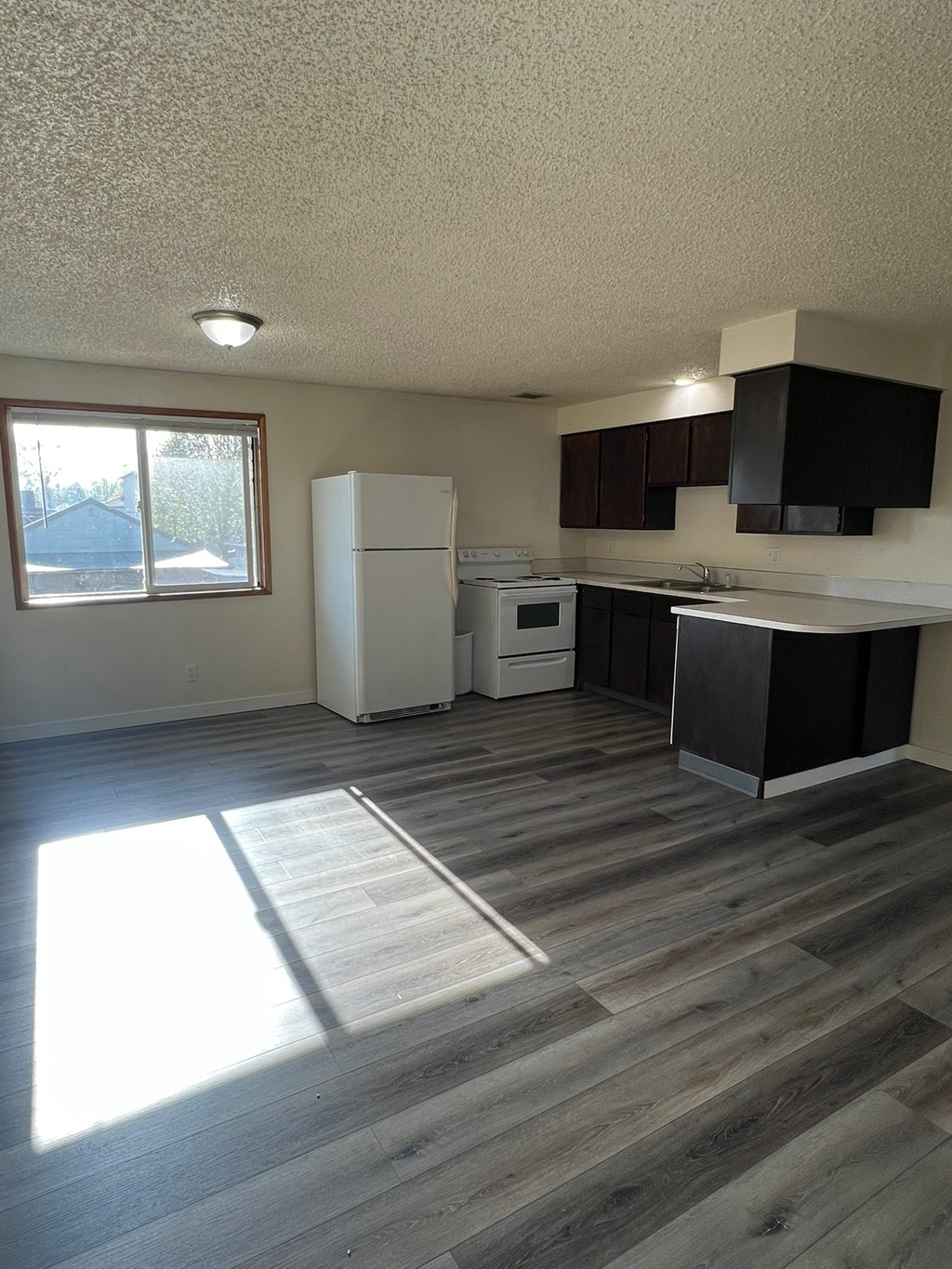 A kitchen with a white refrigerator and wooden floors.