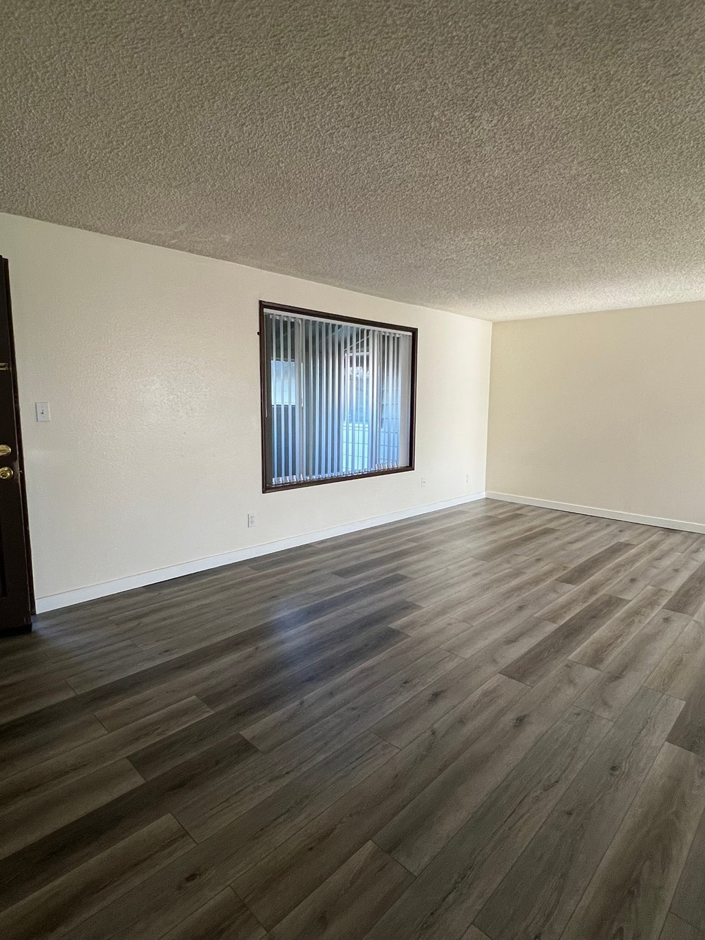 A room with a window and wooden flooring.