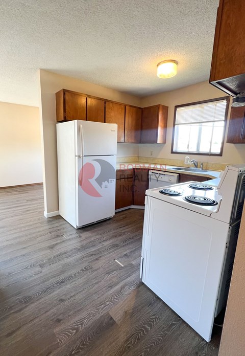 A white fridge and stove in a kitchen with wooden cabinets.