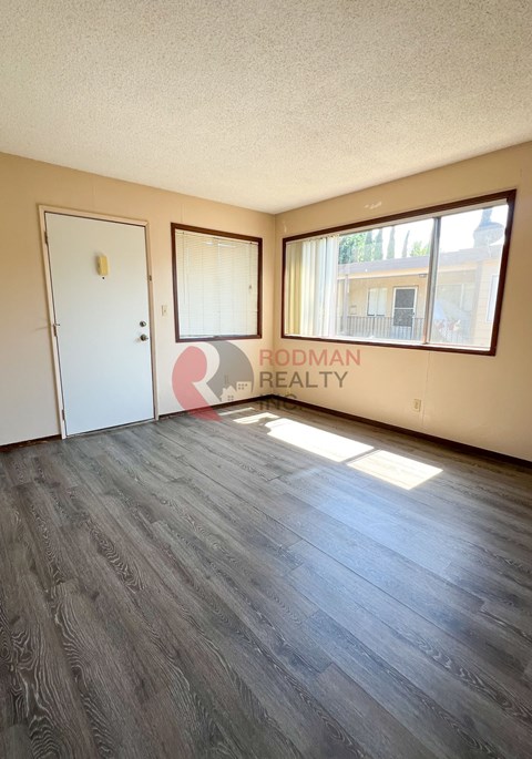 A room with a wooden floor and a window with a view of a building outside.