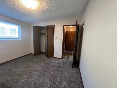 a bedroom with a carpeted floor and a door to a closet and a window