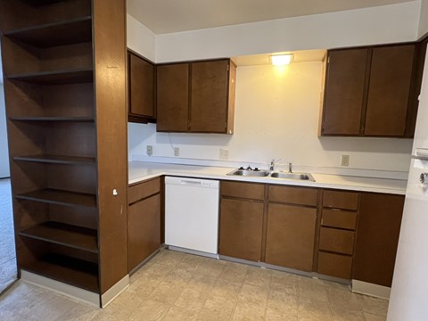 A kitchen with brown cabinets and a white dishwasher.
