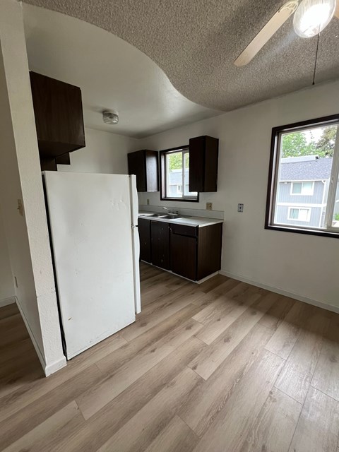 A kitchen with a white refrigerator and wooden floors.