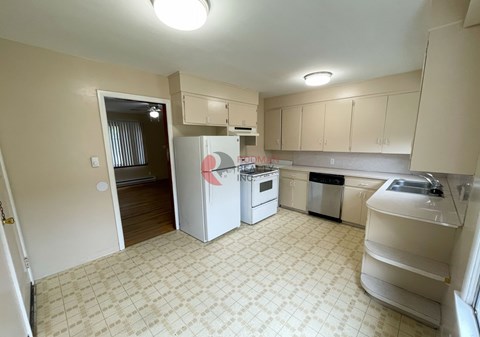 A kitchen with a white fridge and a white dishwasher.