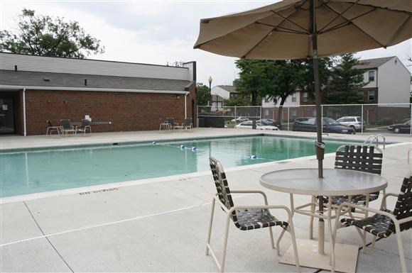 a swimming pool with a table with chairs and an umbrella