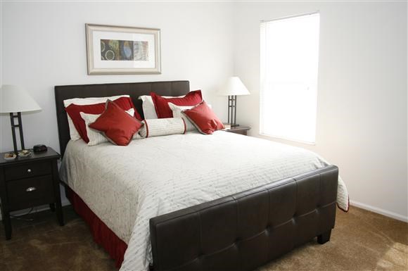 a bedroom with a bed with red and white pillows