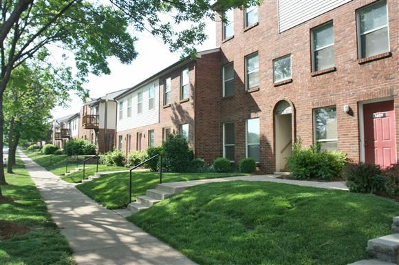 a sidewalk in front of a brick apartment building