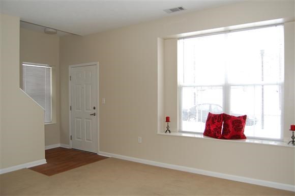 a living room with a window and a red pillow