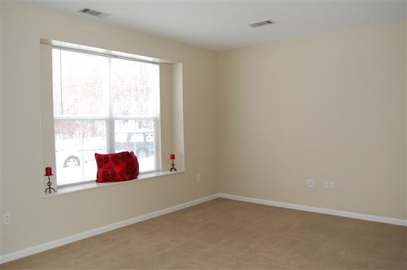 a living room with a window and a red pillow