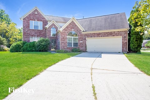 A brick house with a garage and a driveway in front.