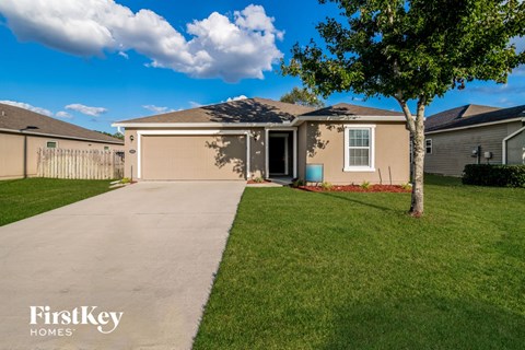 a beige house with a driveway and a tree