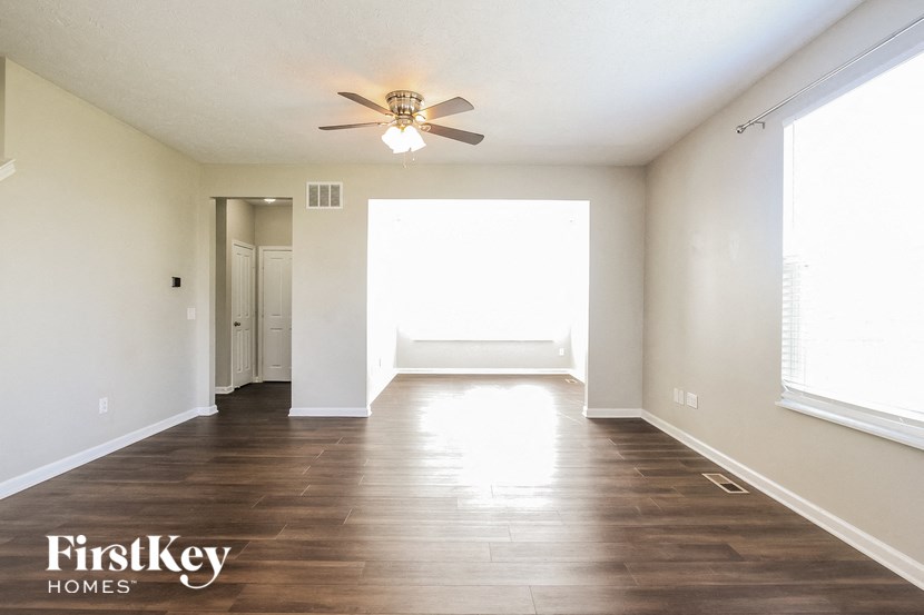 an empty living room with a ceiling fan and a large window