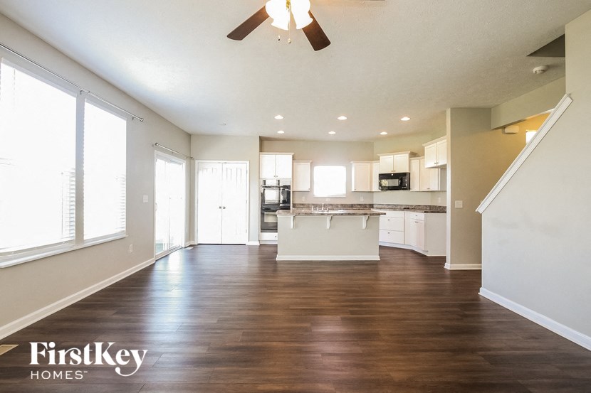 an empty living room and kitchen with a ceiling fan