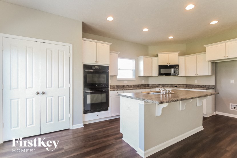 a white kitchen with a marble counter top and