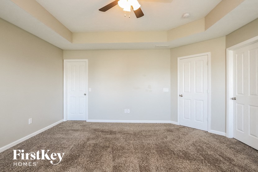 an empty living room with two doors and a ceiling fan