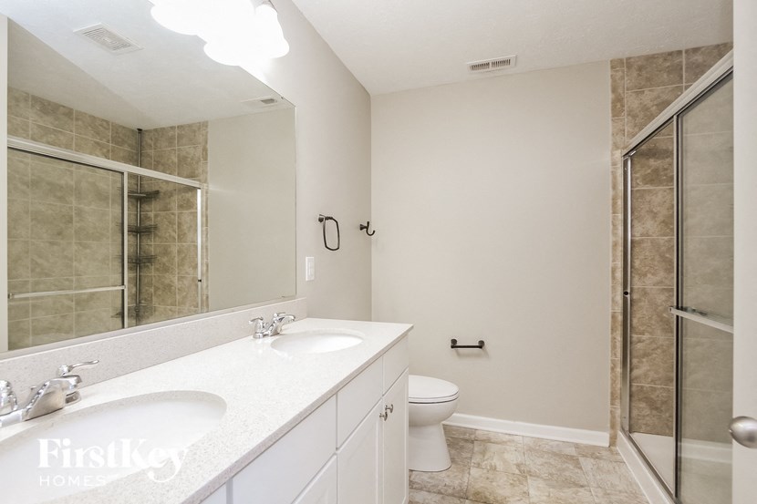 a bathroom with two sinks and a toilet and a shower