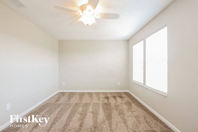 an empty living room with a ceiling fan and a large window