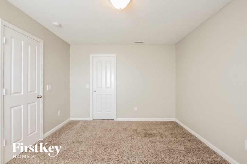 a bedroom with a carpeted floor and a white door