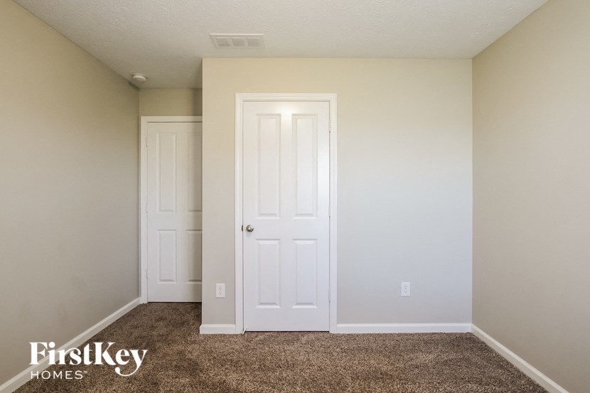 a bedroom with a white door and a carpeted floor