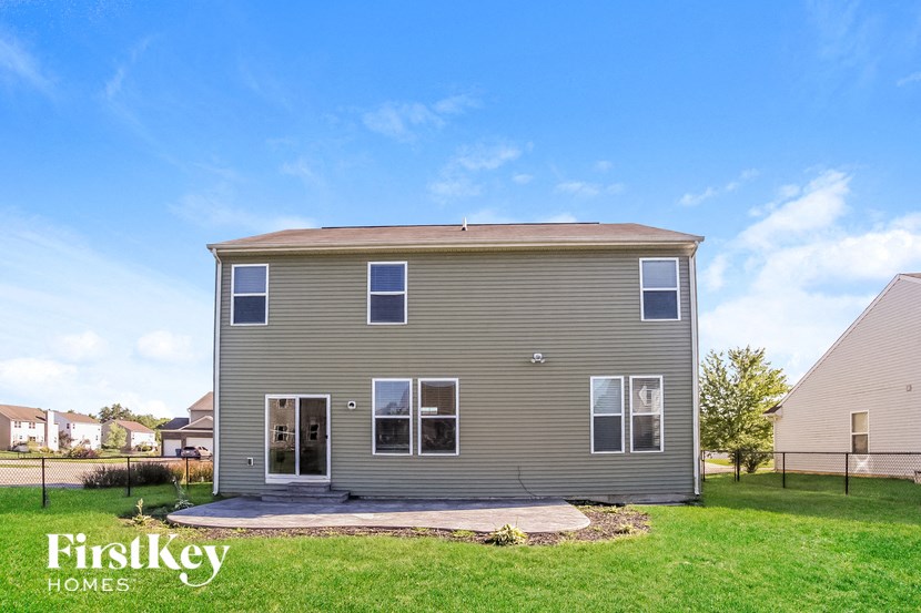 the back of a house with a green lawn and a blue sky