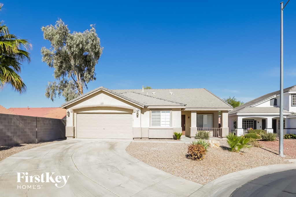 A house with a driveway and a tree in front of it.