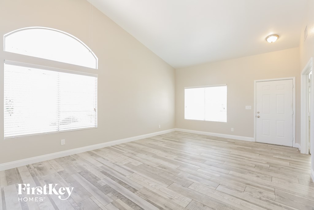 A spacious room with wooden flooring and a large arched window.