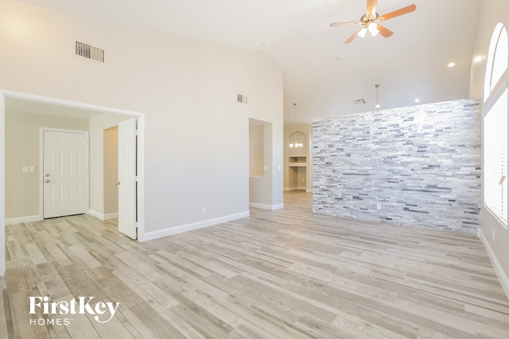 A spacious room with a stone wall and wooden flooring.