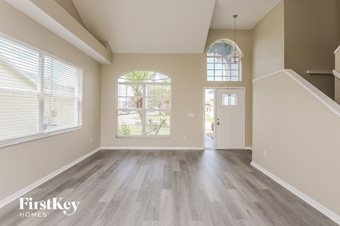 A spacious room with wooden floors and a large arched window.