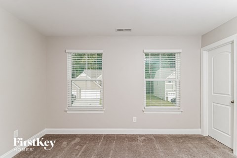 a bedroom with two windows and a carpeted floor