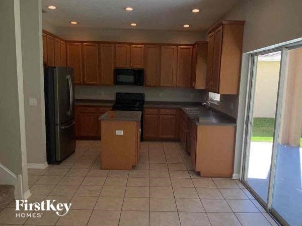 a kitchen with wooden cabinets and a black refrigerator