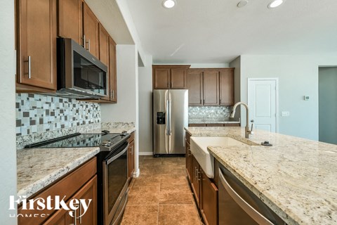A kitchen with brown cabinets and a tile backsplash.