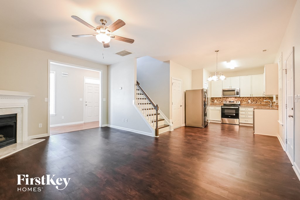 A spacious living room with wood flooring and a staircase leading to the upper level.