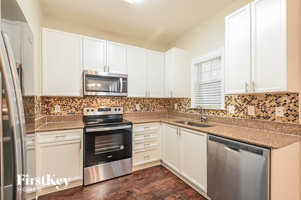 A kitchen with a stove top oven and a microwave on the counter.