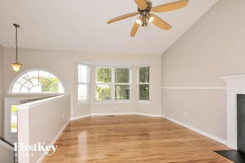 an empty living room with a ceiling fan and a window