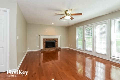 A spacious living room with a fireplace and wood flooring.