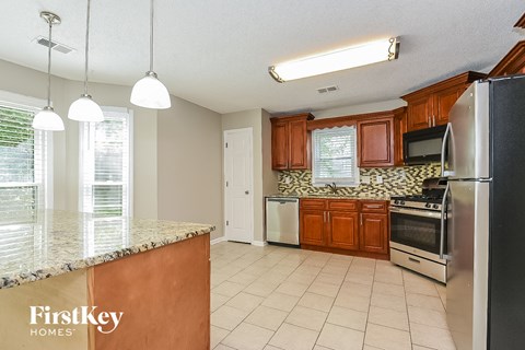 A kitchen with a granite counter top and stainless steel appliances.
