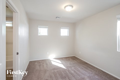 a bedroom with white walls and white carpet and two windows