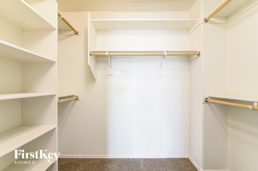 a walk in closet with shelves and a white wall