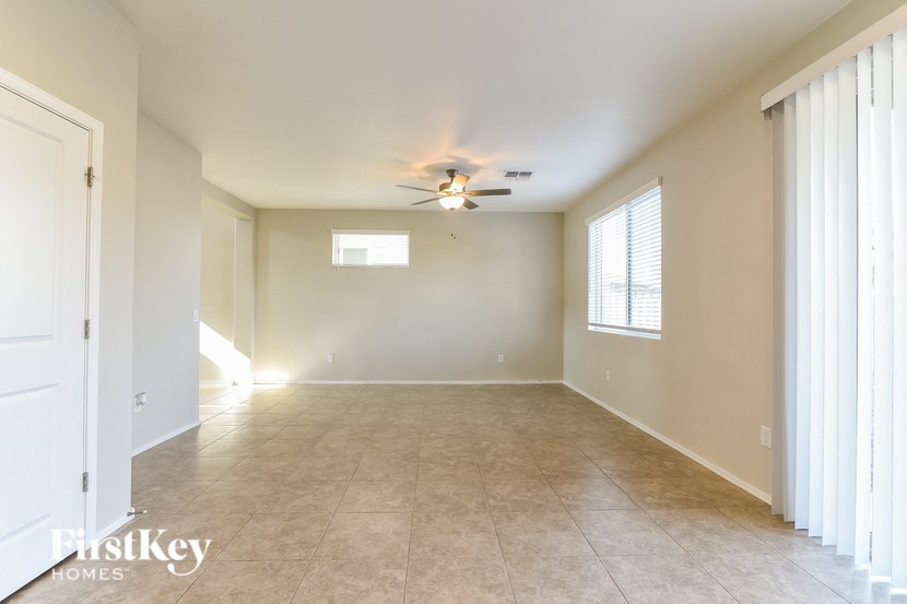 an empty living room with a ceiling fan and a window