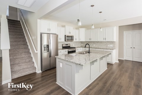 a kitchen with white cabinets and a marble counter top