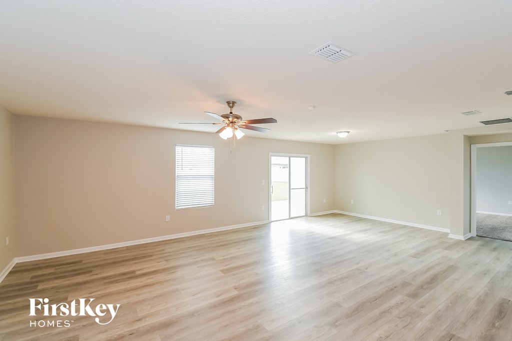 the spacious living room with hardwood floors and a ceiling fan