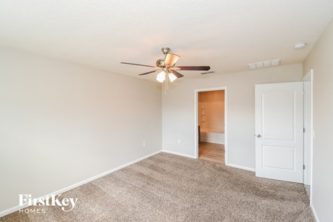 a spacious living room with carpet and a ceiling fan