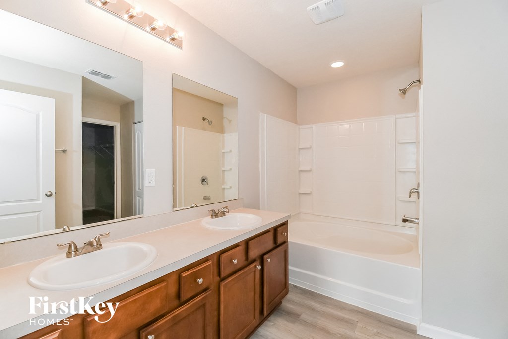 a bathroom with two sinks and a tub and a large mirror