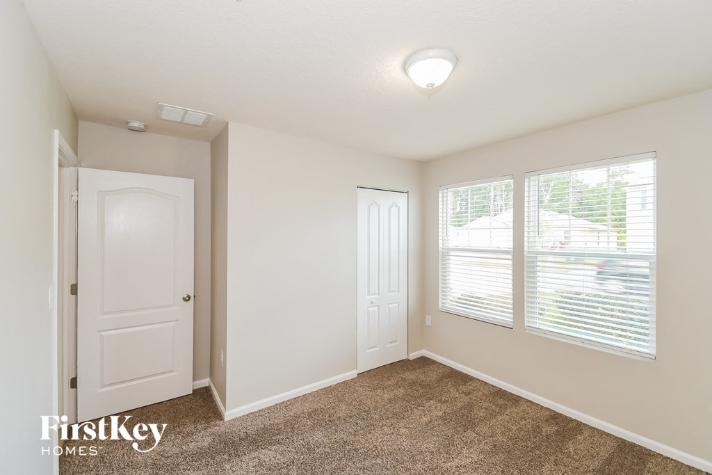 a bedroom with two windows and a door and a carpeted floor