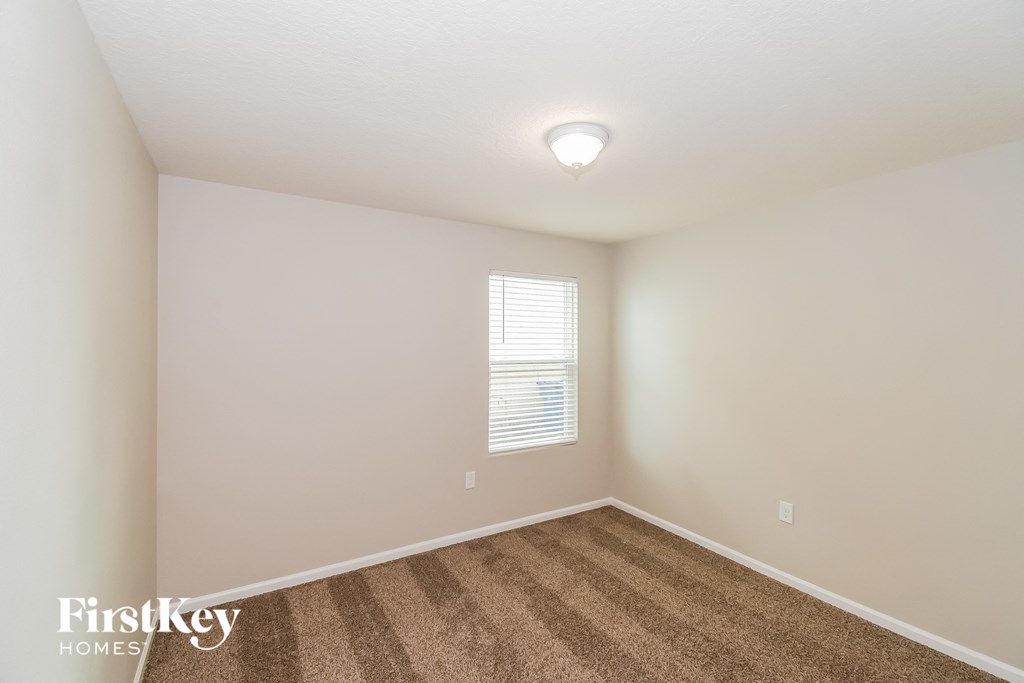 a spacious bedroom with carpet and a window
